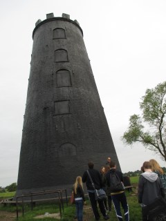 A large black cylinder with wooden boards over the outlines of windows.