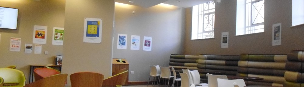 A large white room with wooden chairs and green leather tubes across one wall.